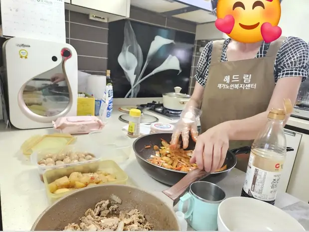 해드림 앞치마를 입은 요양보호사가 어르신의 반찬을 조리하는 모습