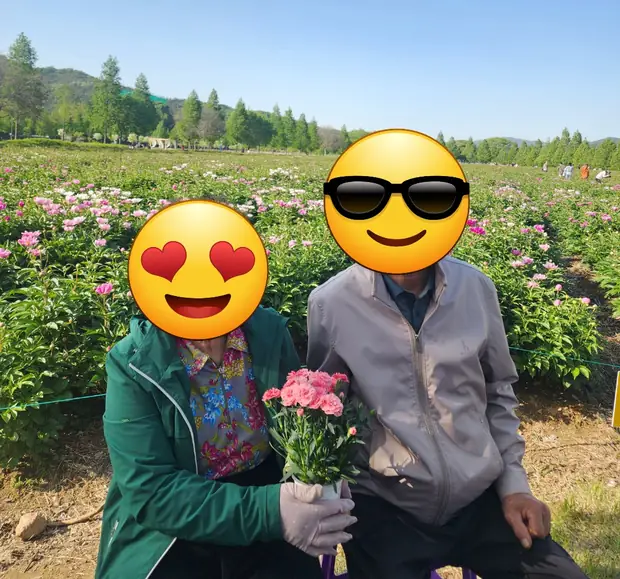 꽃밭에서 나란히 앉아 꽃을 안고 계신 어르신 부부